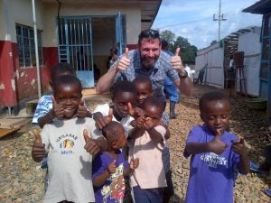 Dr. Brian Bird (Ph.D. '08, DVM '09) outside an Ebola Treatment Unit in Sierra Leone, with a group of kids who had recovered from the virus and were celebrating their discharge.